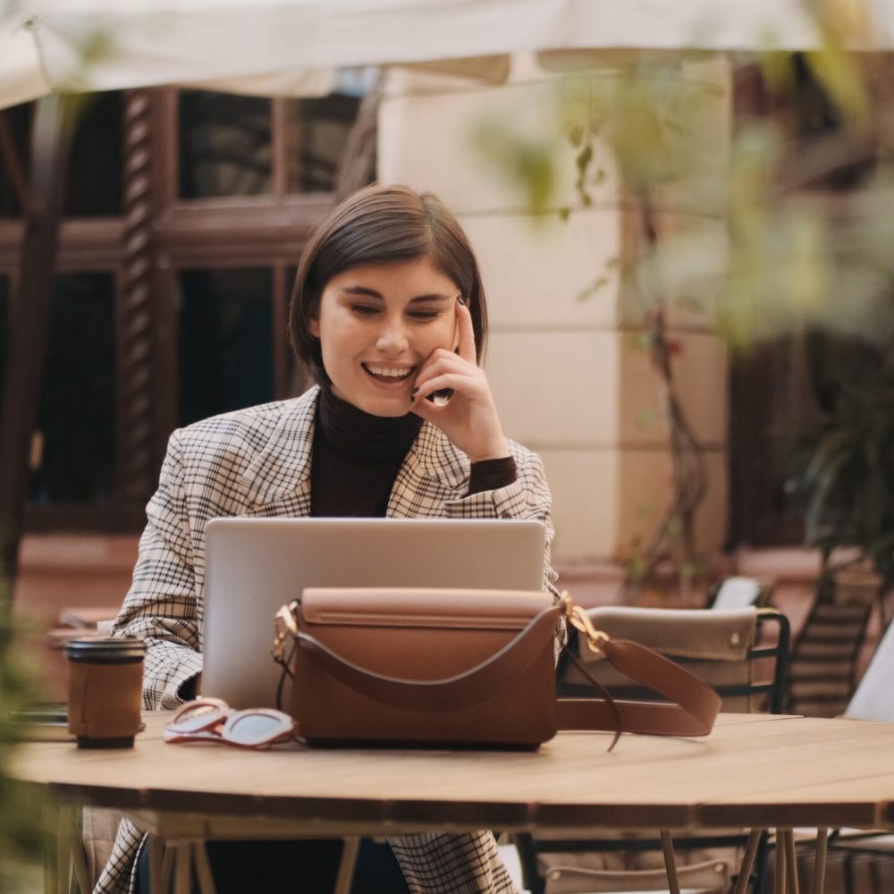 Beautiful female lawyer looking happy talking on video call with customers during coffee break in cafe outdoor. Modern technology